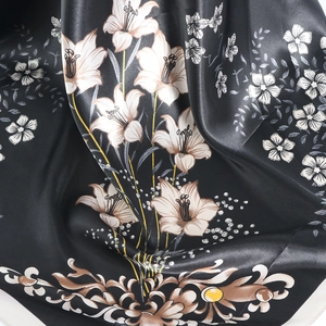 Macro shot of lily floral patterns on smooth black satin silk scarf with soft drapes