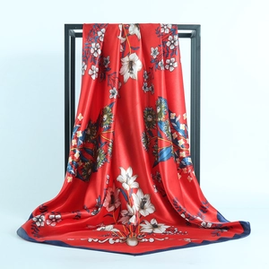 Detail of red satin scarf showing floral lily patterns and silky texture on hanger
