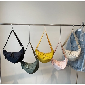 Primer plano de cinco bolsos de media luna en nailon minimalistas en varios colores