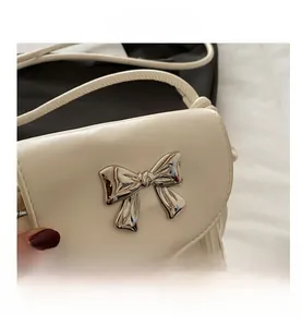 Détail du mini sac blanc avec un nœud argenté et de longues franges à glands