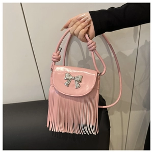 Détail des franges roses et du nœud argenté sur un sac à bandoulière en cuir brillant