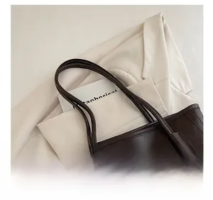 Nahaufnahme der schmalen Doppel-Schultergurte einer dunkelbraunen Tote Bag mit Ledertextur