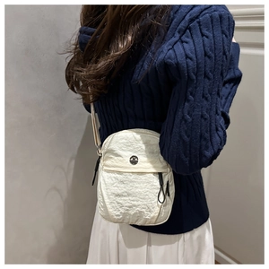 Detailed view of a white nylon crossbody bag with textured fabric and adjustable strap