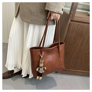 Detailaufnahme der braunen Vintage-Einkaufstasche mit Lederstruktur und Hasenanhänger
