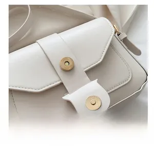 Close-up of the magnetic hardware clasp on a white vintage leather crossbody bag