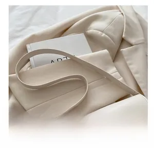 Detail view of beige crossbody bag with magnetic snap and matching slim shoulder strap