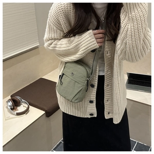 Close-up of lightweight green nylon crossbody bag with multiple zip compartments and strap