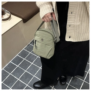 Detailed shot of olive green nylon crossbody bag with metallic M logo and wide strap