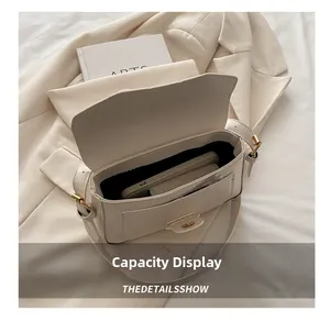 Detail view of cream flap bag interior showing capacity for smartphone and small purse