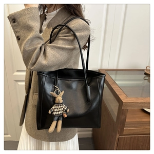 Detail einer schwarzen Leder-Tote-Bag mit Hasenanhänger an der Schulter des Models