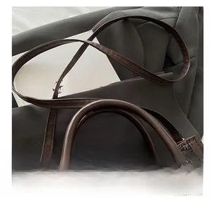Close-up of monogram pattern tote bag with adjustable leather straps and gold hardware