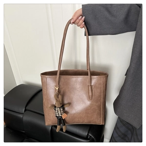 Detailansicht der braunen PU-Leder-Tote-Bag mit Vintage-Textur und Strick-Hasenanhänger