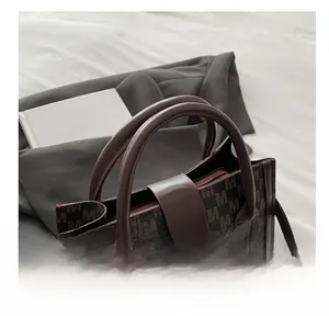 Detail of dark brown monogram leather handbag with golden metal logo on a soft background