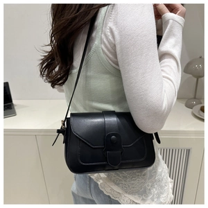 Detail of a black leather retro square bag shown as a crossbody on a knit sweater