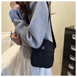 Detailed side view of a black nylon crossbody bag on model with wide fabric strap