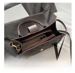 Detail view of brown monogram canvas tote bag showing interior space with a smartphone