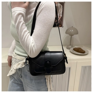 Detail view of the matte black faux leather shoulder bag with a stylish flap and vertical strap