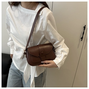 Close-up of a brown retro crossbody bag featuring a round buckle and fine leather texture