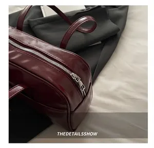 Detail of smooth silver zipper and glossy wine red leather texture on the handbag