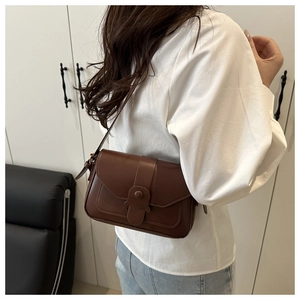 Side view of dark brown vintage flap crossbody bag worn with a white shirt and jeans