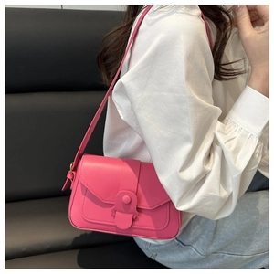 Magenta square crossbody bag with magnetic flap worn by model over white top and denim