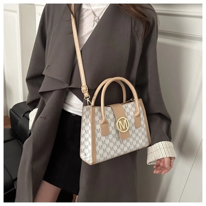 Detail of the monogram canvas tote bag featuring premium leather trim and golden metal clasp