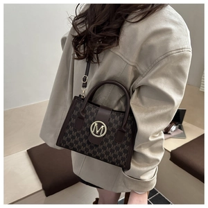 Detail of retro monogram crossbody bag with golden M buckle on white jacket model