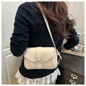 Chic beige shoulder bag with flap closure and tassel detail worn by a model