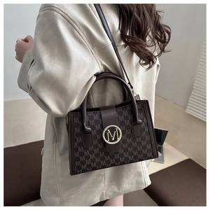 Detail of vintage monogram brown tote bag featuring gold metallic M logo and leather handle