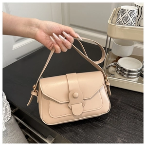 Close-up of beige square leather handbag with unique bar buckle on lifestyle background