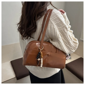Detail of a brown PU leather shoulder bag with magnetic pocket and wooden bead pendant