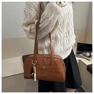 Brown faux leather bowling bag shown with wooden bead charm and long shoulder strap