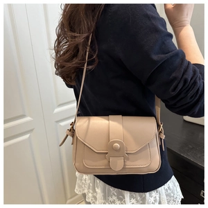Model wearing a minimalist apricot crossbody bag made of smooth synthetic leather