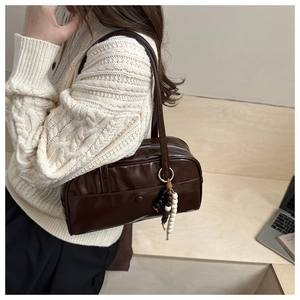 Close-up of dark brown leather shoulder bag with vintage wooden beads and front pocket