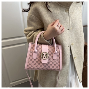 Detail shot of light pink bag with M-pattern print and golden metal buckle on beige coat