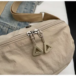 Close-up of smooth double zipper with triangular pulls on a beige nylon dumpling bag