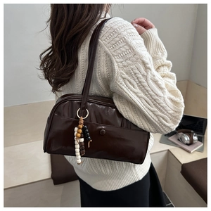 Detail view of deep brown vintage handbag with glossy finish and beaded tassel accessory