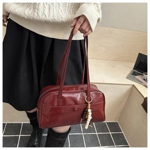 Close-up of a glossy burgundy leather bowling bag with vintage charm and beaded charm