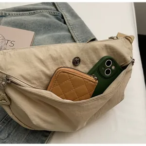 Detail view of large beige nylon crossbody bag showing spacious interior with zipper pockets
