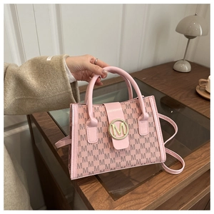 Close-up of pink structured handbag featuring black M patterns and golden logo buckle