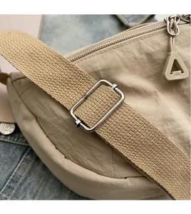 Detail of adjustable woven shoulder strap and triangle zipper pull on beige nylon bag