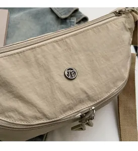 Detail of beige nylon dumpling bag showing water-repellent texture and dual metal zippers