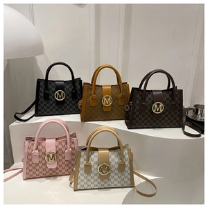 Detail view of five textured tote bags with M-print patterns and gold metal buckles