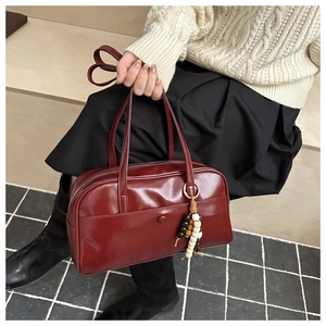 Close-up of wine red bowling handbag with decorative wooden beads and a front snap pocket