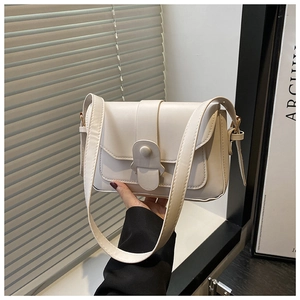 Detail of off-white PU leather crossbody bag with flap and metal clasp being held by hand