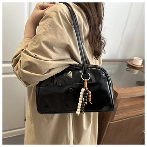 Detail of black patent leather bowling bag with multi-color wooden bead tassel