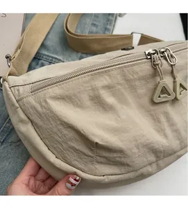 Detail of light khaki nylon dumpling bag featuring dual silver zippers and wide fabric strap