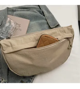 Detail of beige nylon dumpling bag showing front zipper pocket storage and large capacity