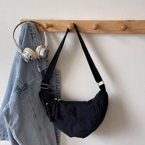 Borsa a tracolla nera a mezzaluna minimalista con cerniera intrecciata appesa a un appendiabiti