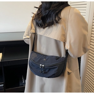 Detail of black nylon dumpling crossbody bag with adjustable strap and metal logo